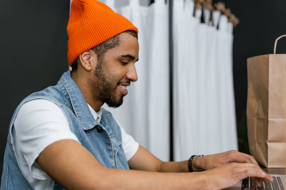 Uśmiechnięta osoba pracująca przy laptopie w kawiarni.